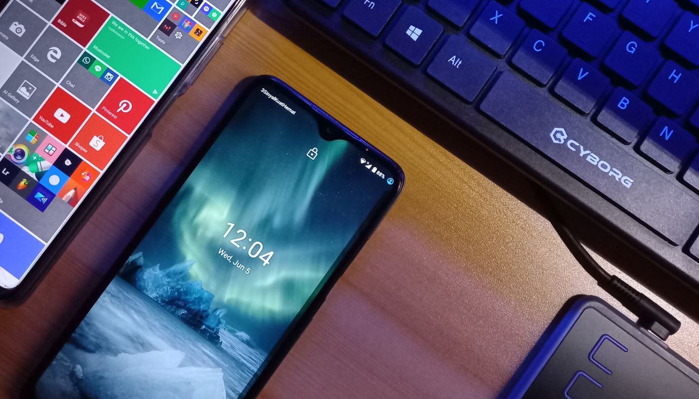 Two smartphones beside a computer keyboard